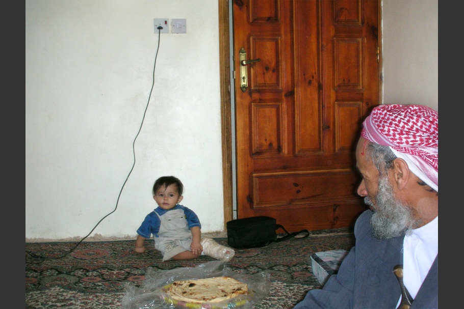 A bearded man with an infant sitting under a power cord.