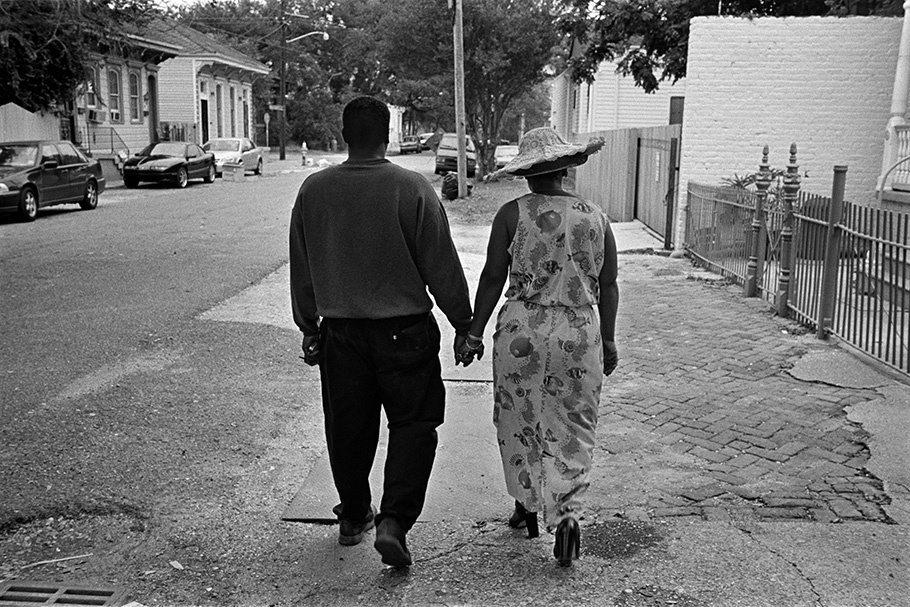 Couple holding hands, viewed from behind.