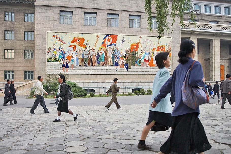 People walking by a mural.