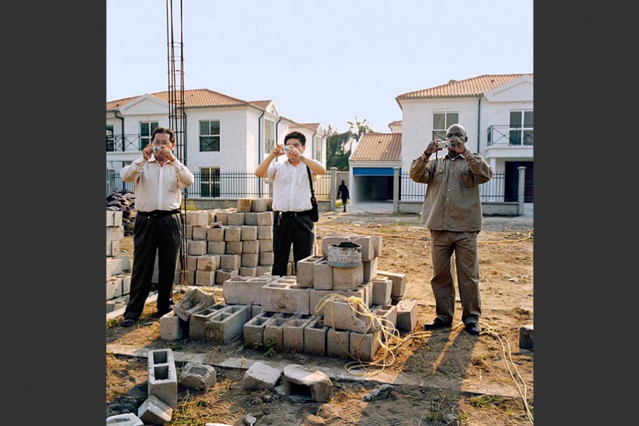 Three men photographing a construction site.
