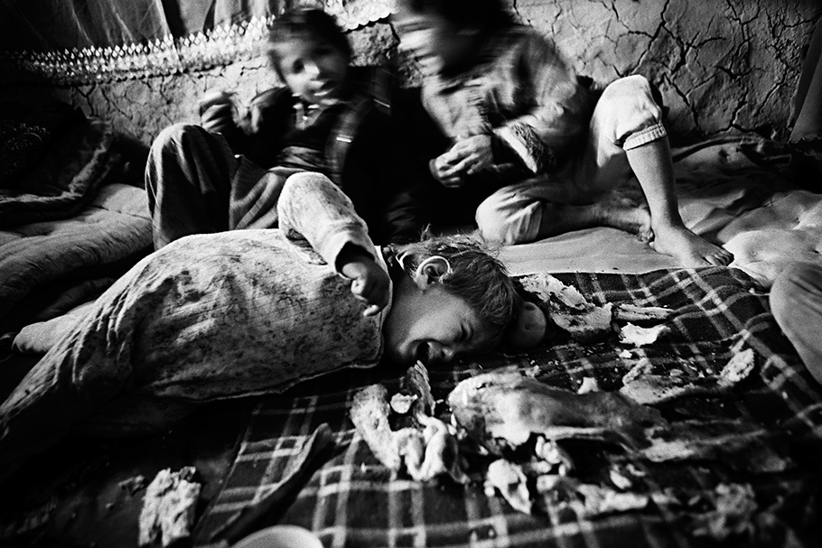 Child lying on floor, two more in background.