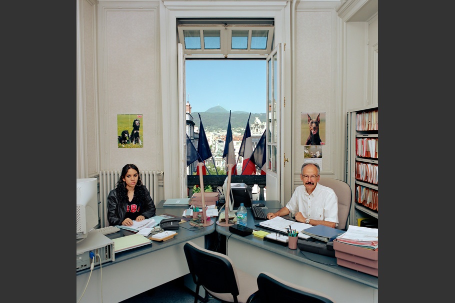 Two desks, open window with French flags.