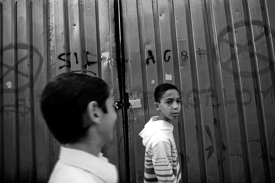 Boys in front of fence with graffiti.