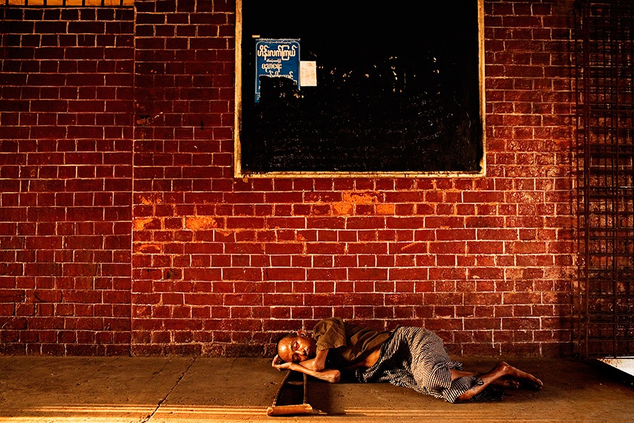 Man sleeping in front of a brick wall. 
