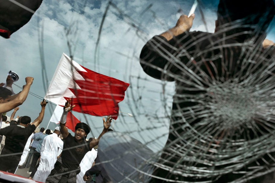 A man holding a flag seen through broken glass.