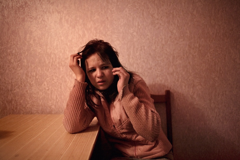 A crying woman leans on a desk.