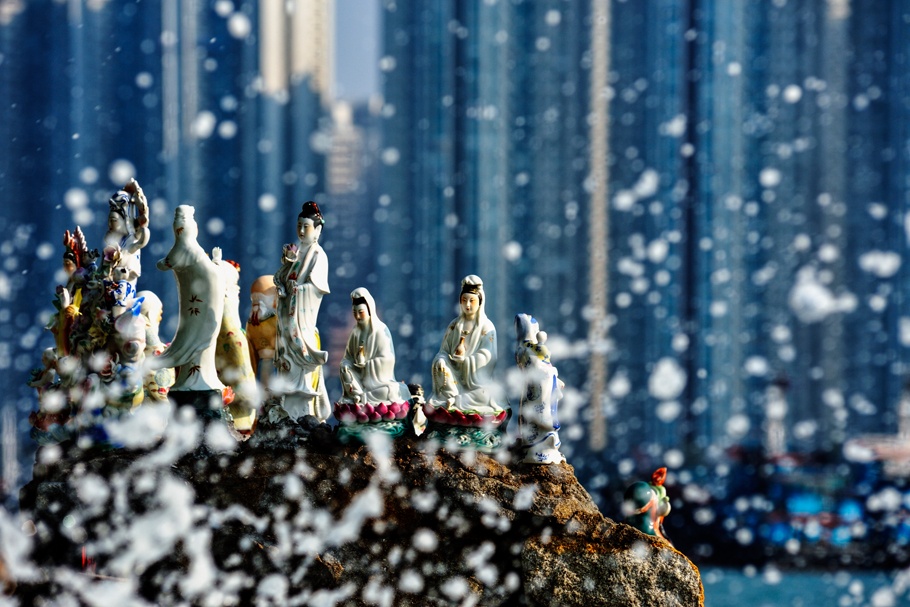 Miniature statues arranged on a wave-sprayed rock