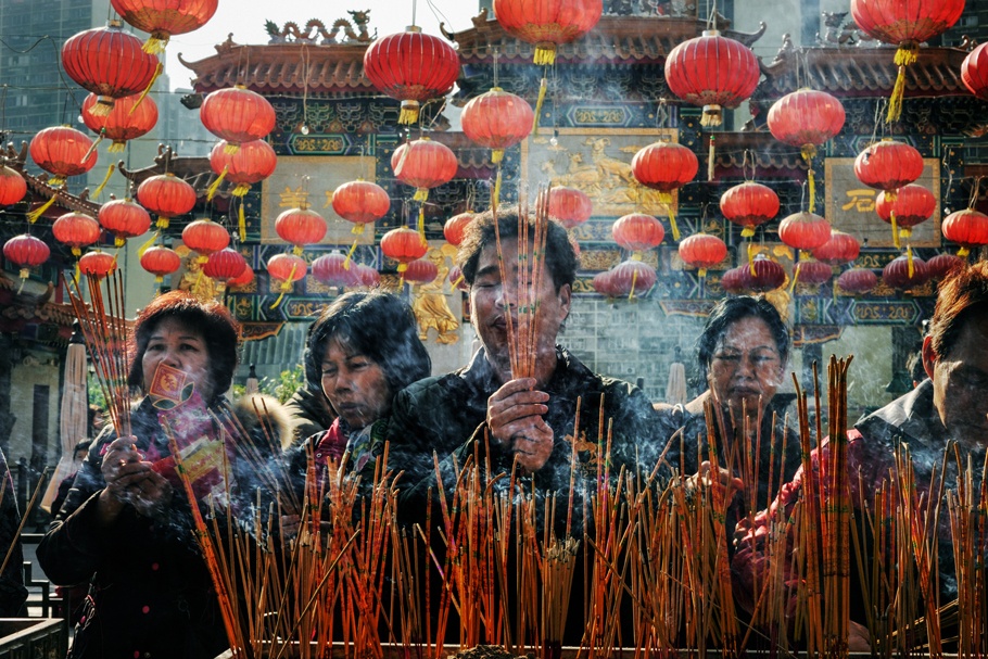 People burning incense and praying at a temple