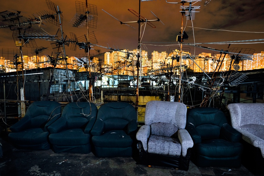Armchair and antennas on a rooftop, with cityscape in the background