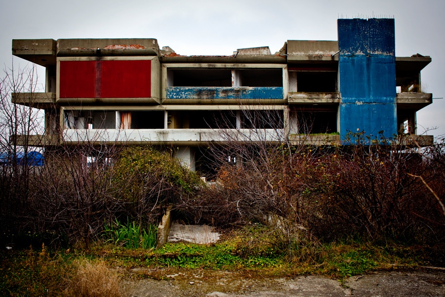 Abandoned factory with red and blue external wall panels. 