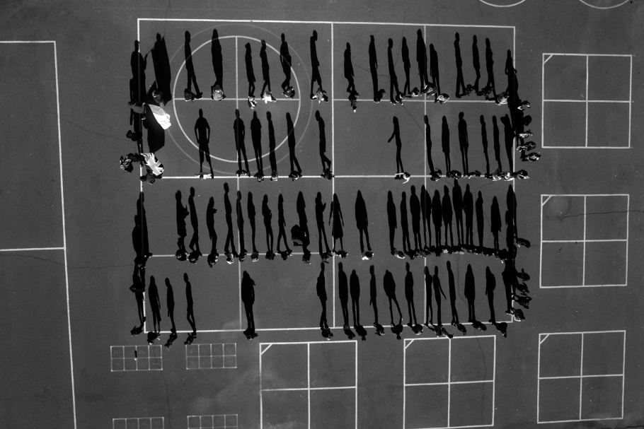 Aerial photograph of schoolyard with shadows of students lined up in four rows