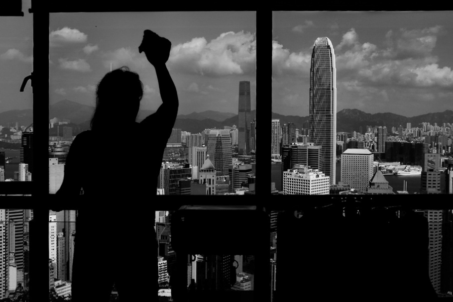 A woman cleaning the window of a skyscraper.