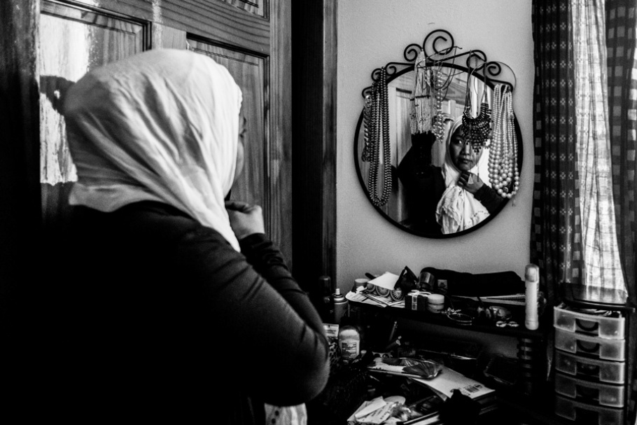 A woman wearing a headscarf and looking in a mirror.