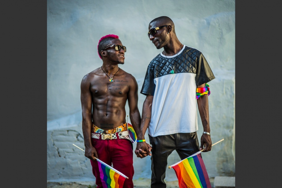Two men holding rainbow flags and holding hands