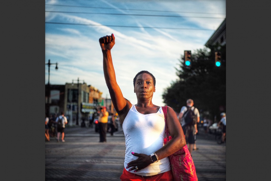 A woman standing in the street with her fist raised.
