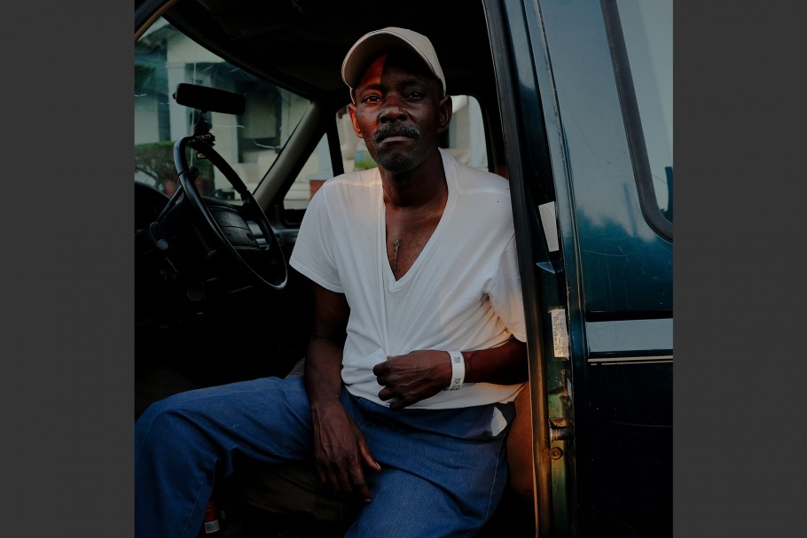 A man sitting in a truck with the door open.