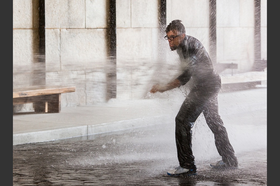 Dread Scott standing while being sprayed by high-pressure water jets.