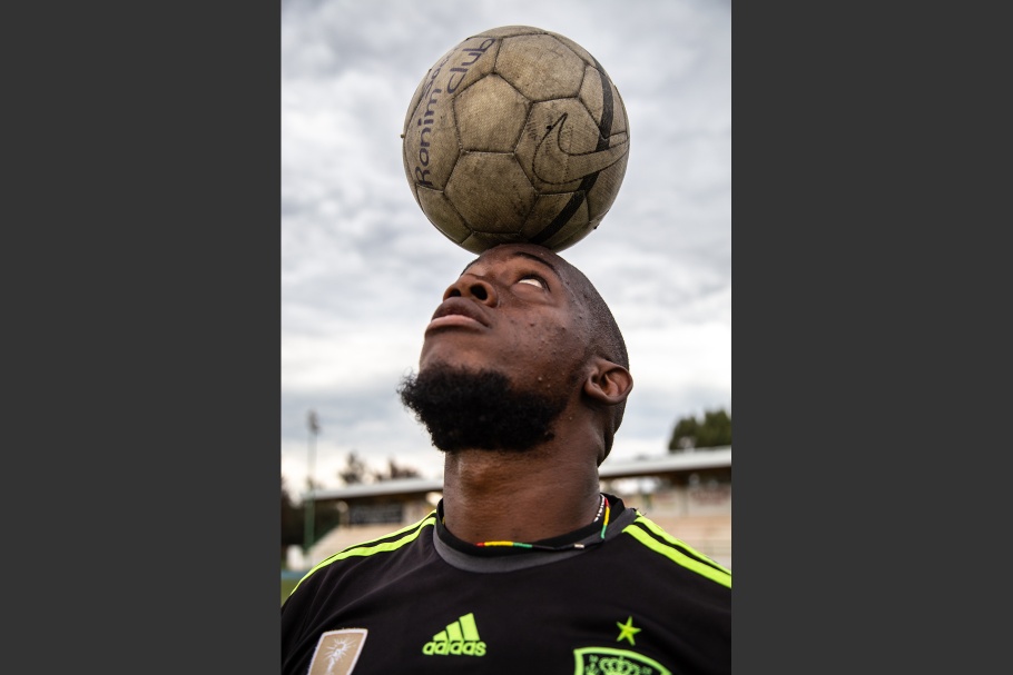 A man balancing a soccer ball on his head