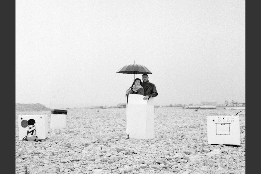 A man with a woman holding an umbrella outside, standing in a box