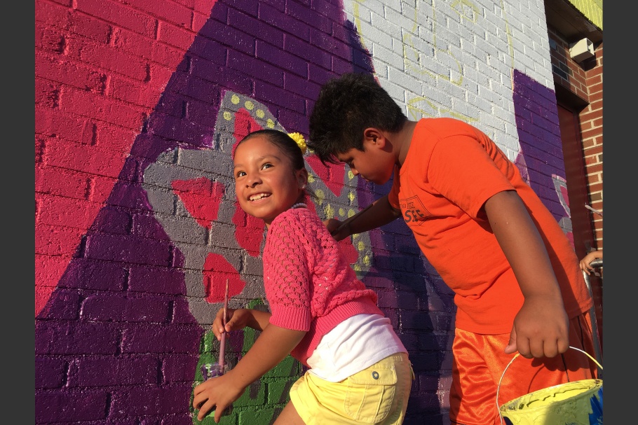 A girl and a boy painting a mural