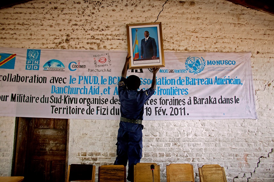 Man hanging a photo of Joseph Kabila.