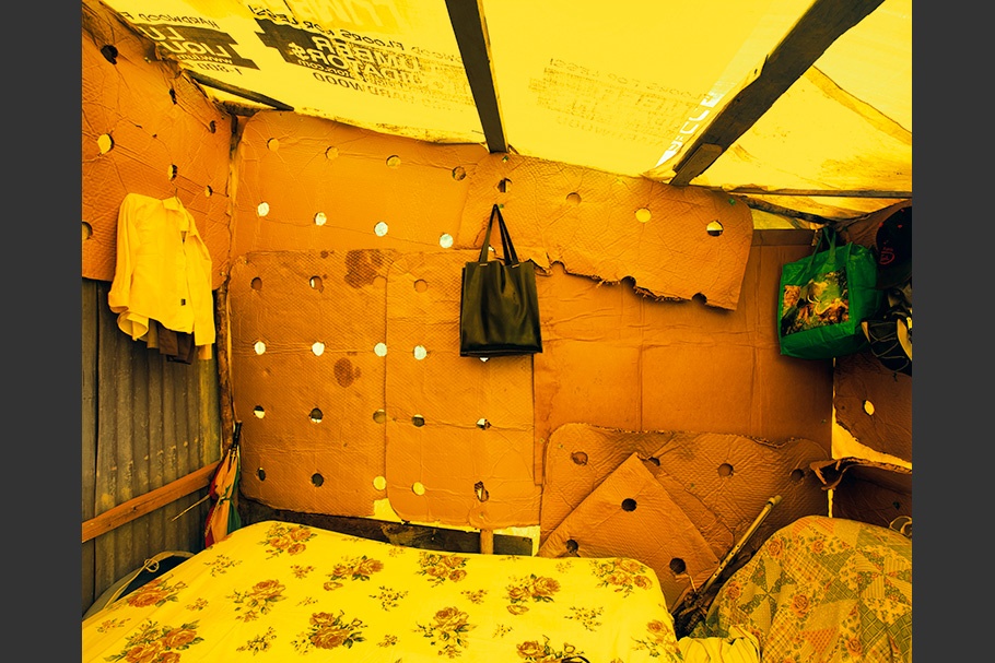 Cardboard and yellow tarp form a temporary home.