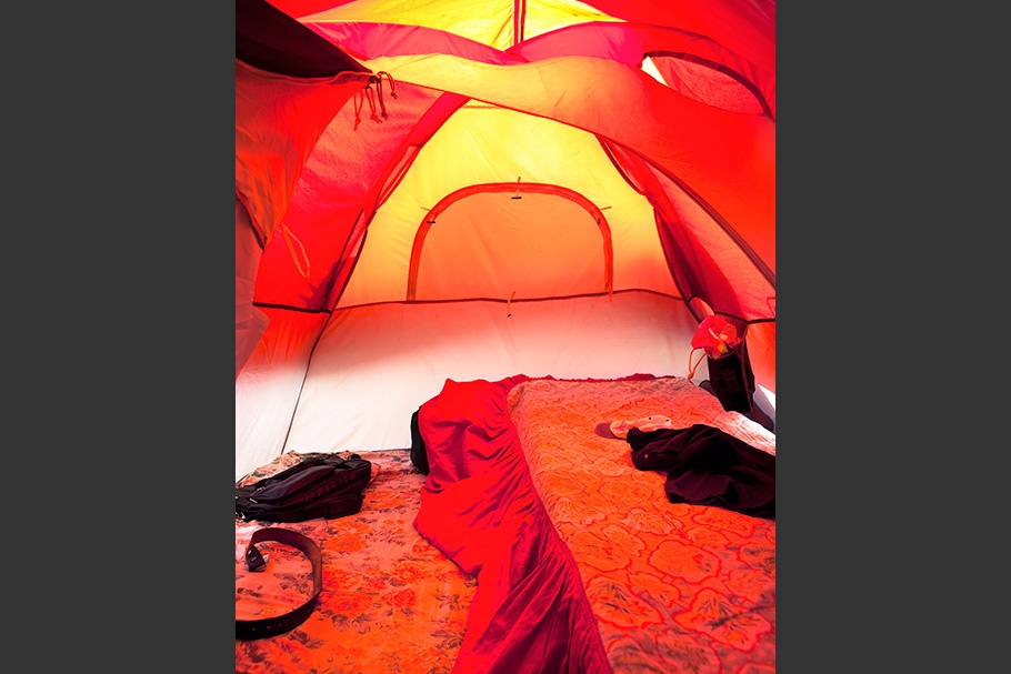 A bed in an orange tent.