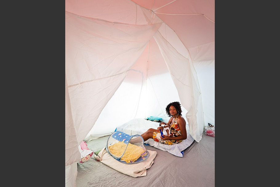 Woman sitting in a tent with baby.