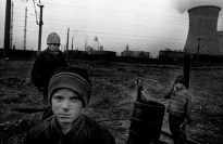 Three boys in front of a power plant.