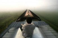 A boy riding on top of a train.