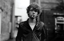 Teenage boy in leather jacket smoking a cigarette.