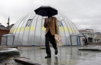 Man with umbrella in front of dome.